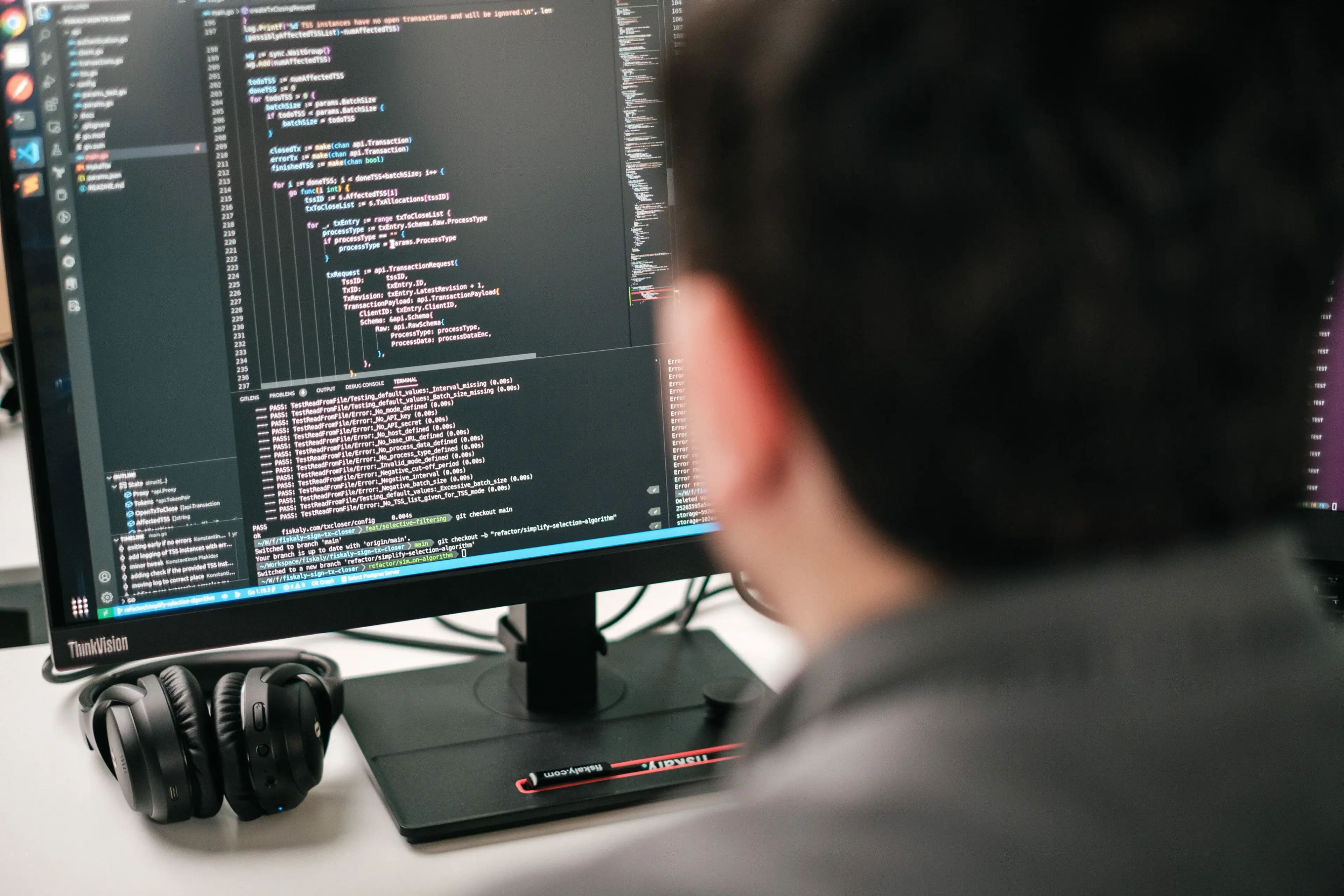 Person's head from the back, looking at the computer monitor with code on it
